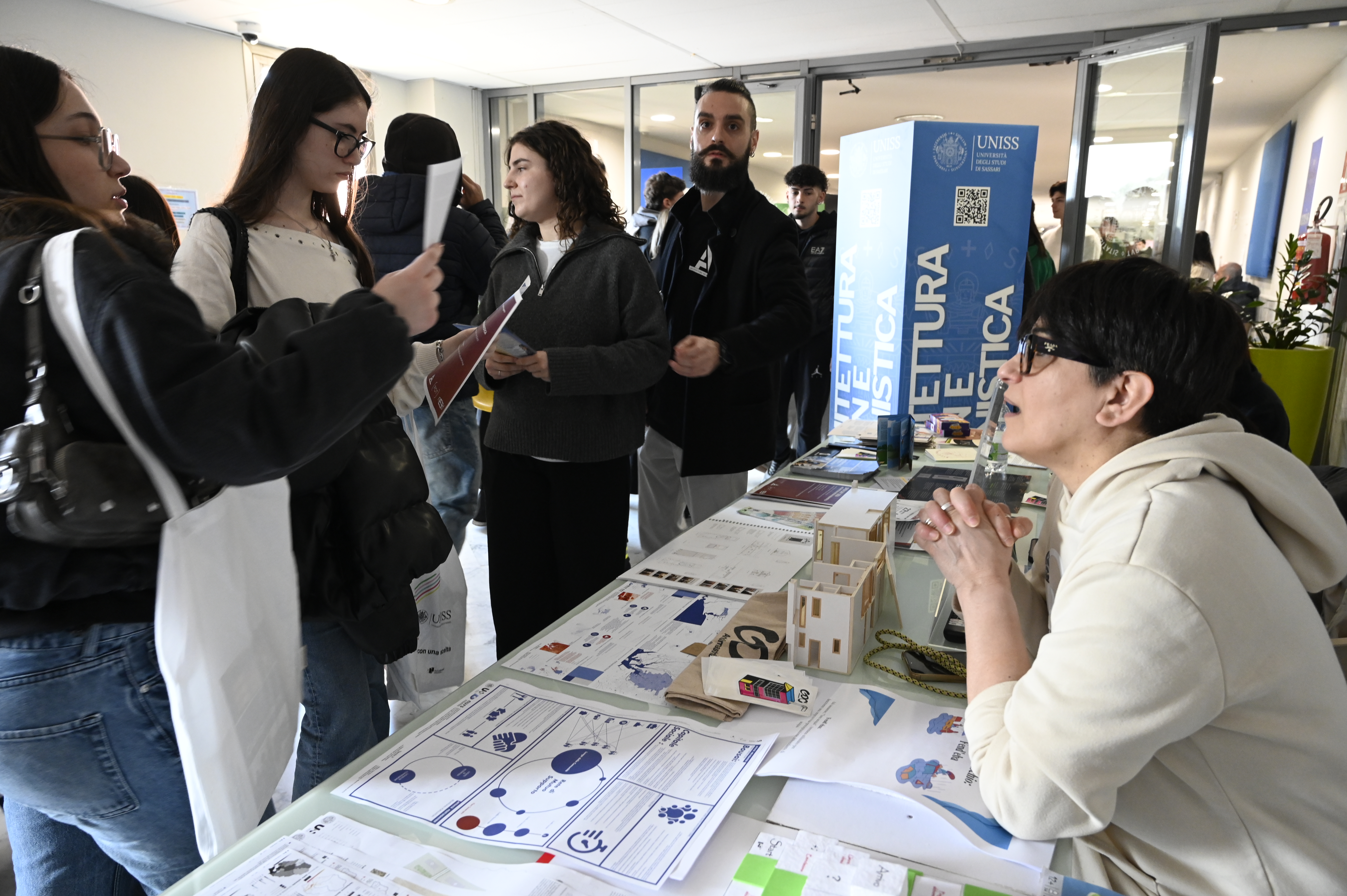 Momento di confronto tra studenti e referente presso uno stand UNISS, con materiali espositivi e informazioni sui percorsi universitari
