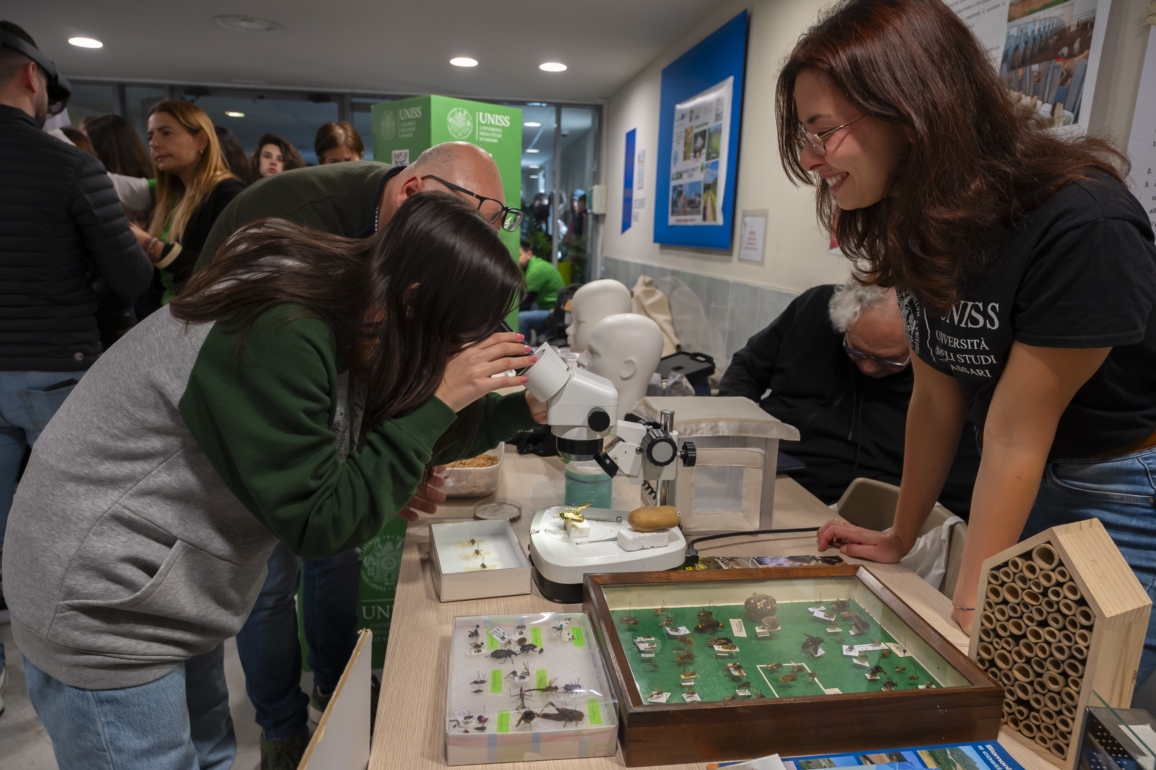 Studentessa osserva al microscopio in uno stand scientifico UNISS, durante le Giornate dell’Orientamento.