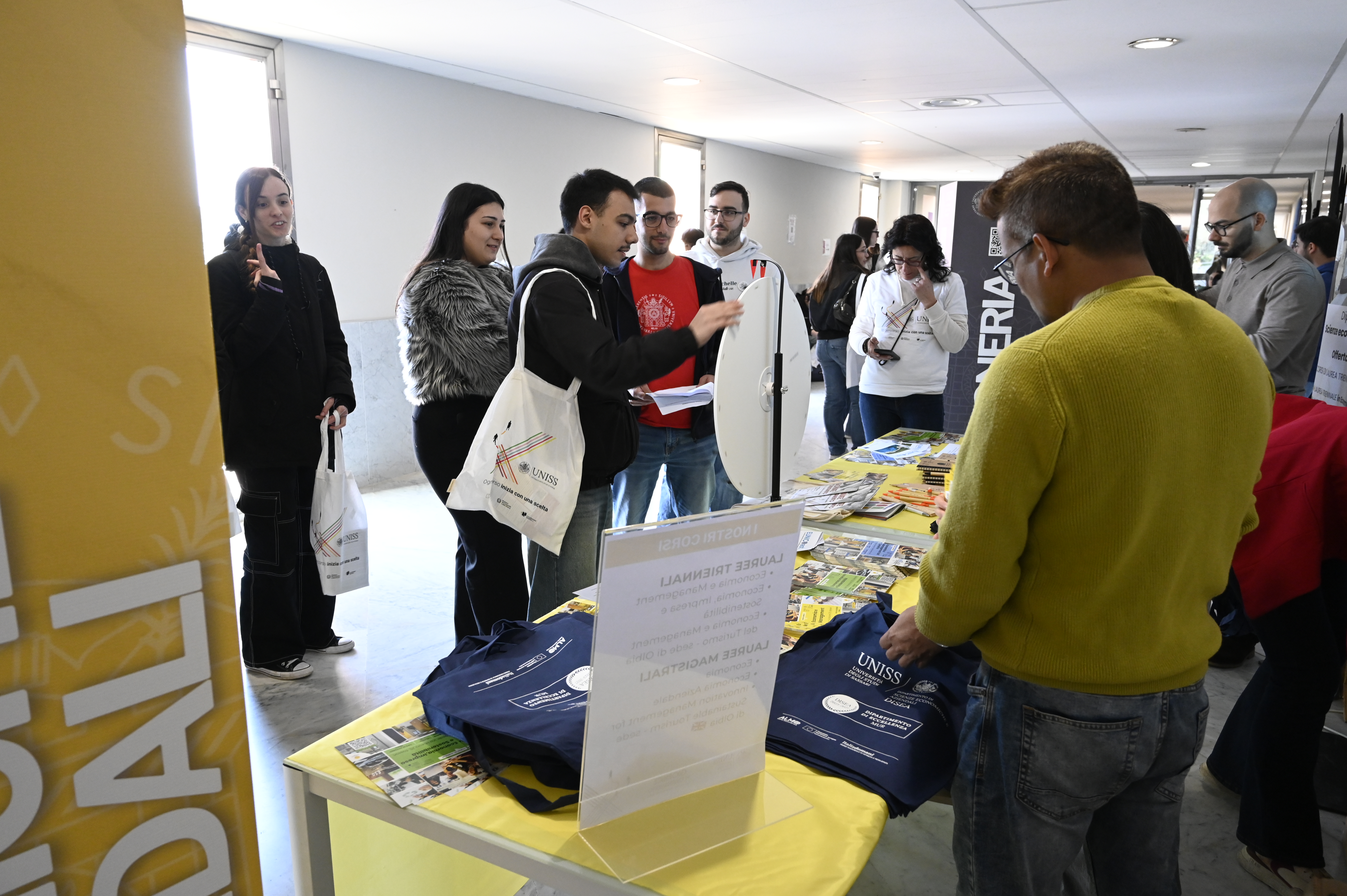 Stand informativo UNISS dedicato ai corsi di laurea, con studenti in visita, materiale promozionale e attività di accoglienza durante l’orientamento