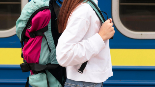 Studentessa con zaino in spalla che cammina accanto a un treno