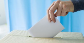 Una mano che inserisce una scheda elettorale in un urna di voto