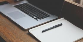 Foto Recruiting Day Athena computer portatile su scrivania marrone con block notes e penna